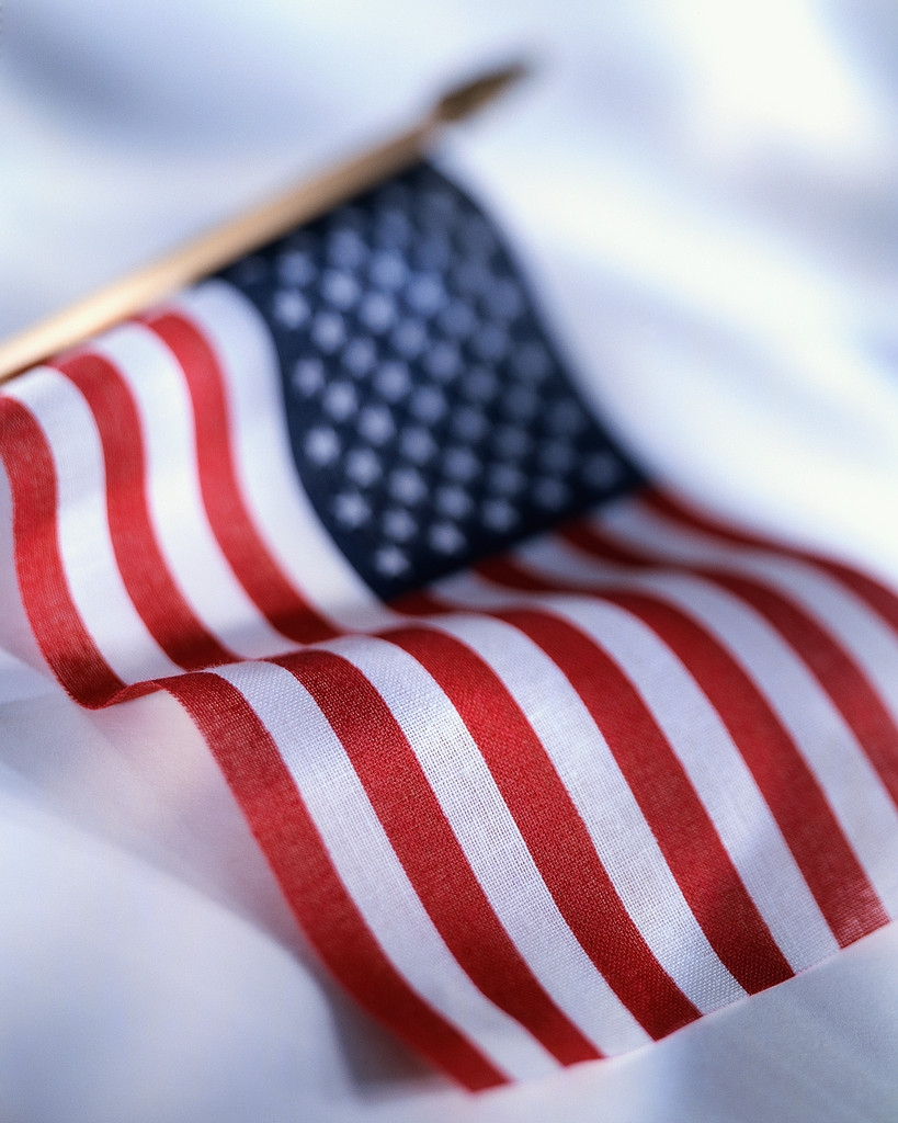 Close-up of a small American flag on a pole, showing red and white stripes with a blue field containing white stars.