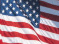 The United States flag with red and white stripes and white stars on a blue field waves in the wind.