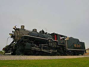 Steam locomotive 630 on a track, displaying its black exterior and front chimney, with grass in the foreground.