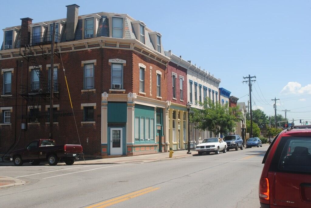 Close-up view of historic brick buildings with decorative trim, trees along the sidewalk, and storefront awnings